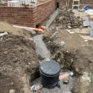 Commercial drainage installation showing inspection chamber and pipe route at a new build development