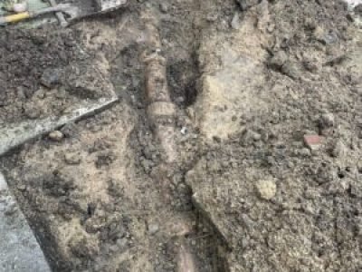 Excavation exposing damaged drain pipe before replacement work in Mancheste