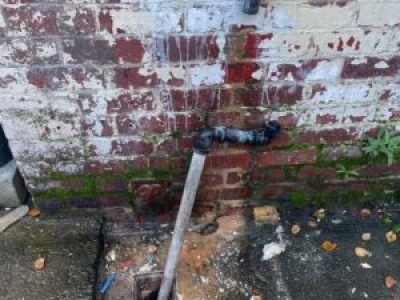 Downpipe connected into new gully during drainage repairs in Salford, Greater Manchester.