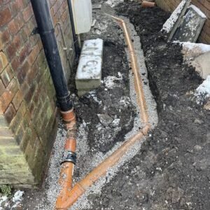 Residential drain installation in Greater Manchester with new pipework laid in a trench