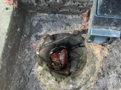 Close-up of damaged gully pot and debris causing drainage issues in Wigan.